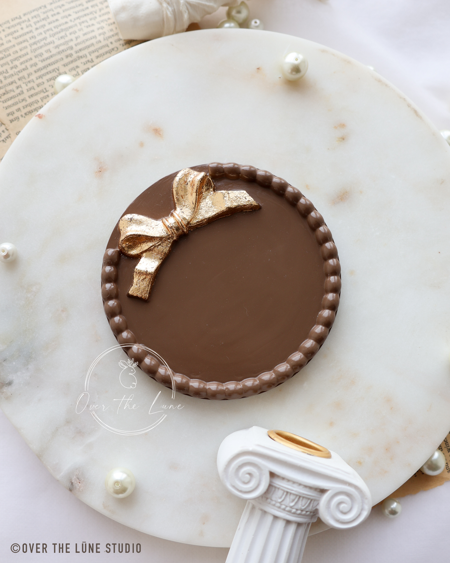 A decorative plaque or sign with a golden bow design displayed on a brown marble surface.